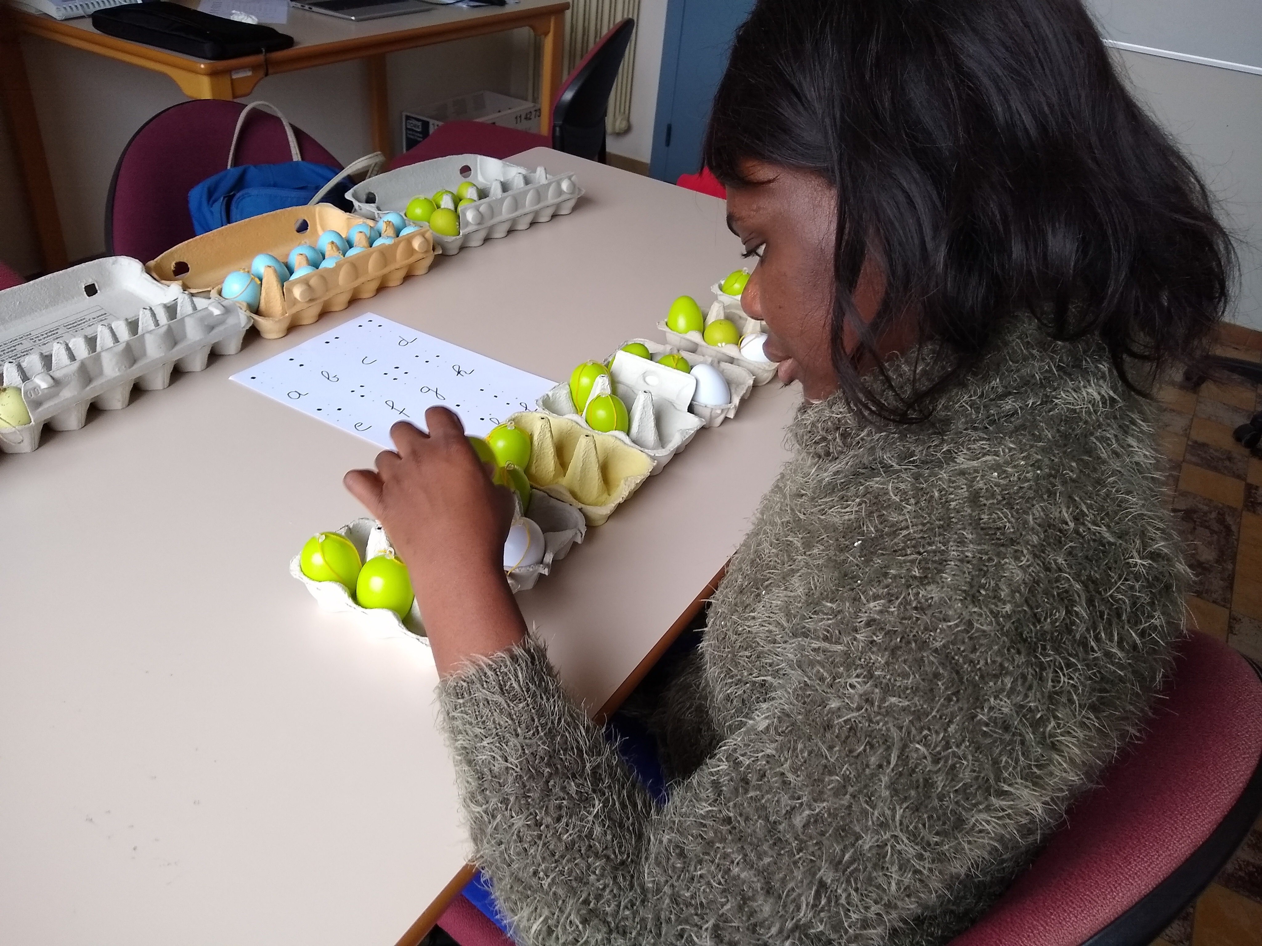 cursist leert het Braille-alfabet aan de hand van eierdozen
